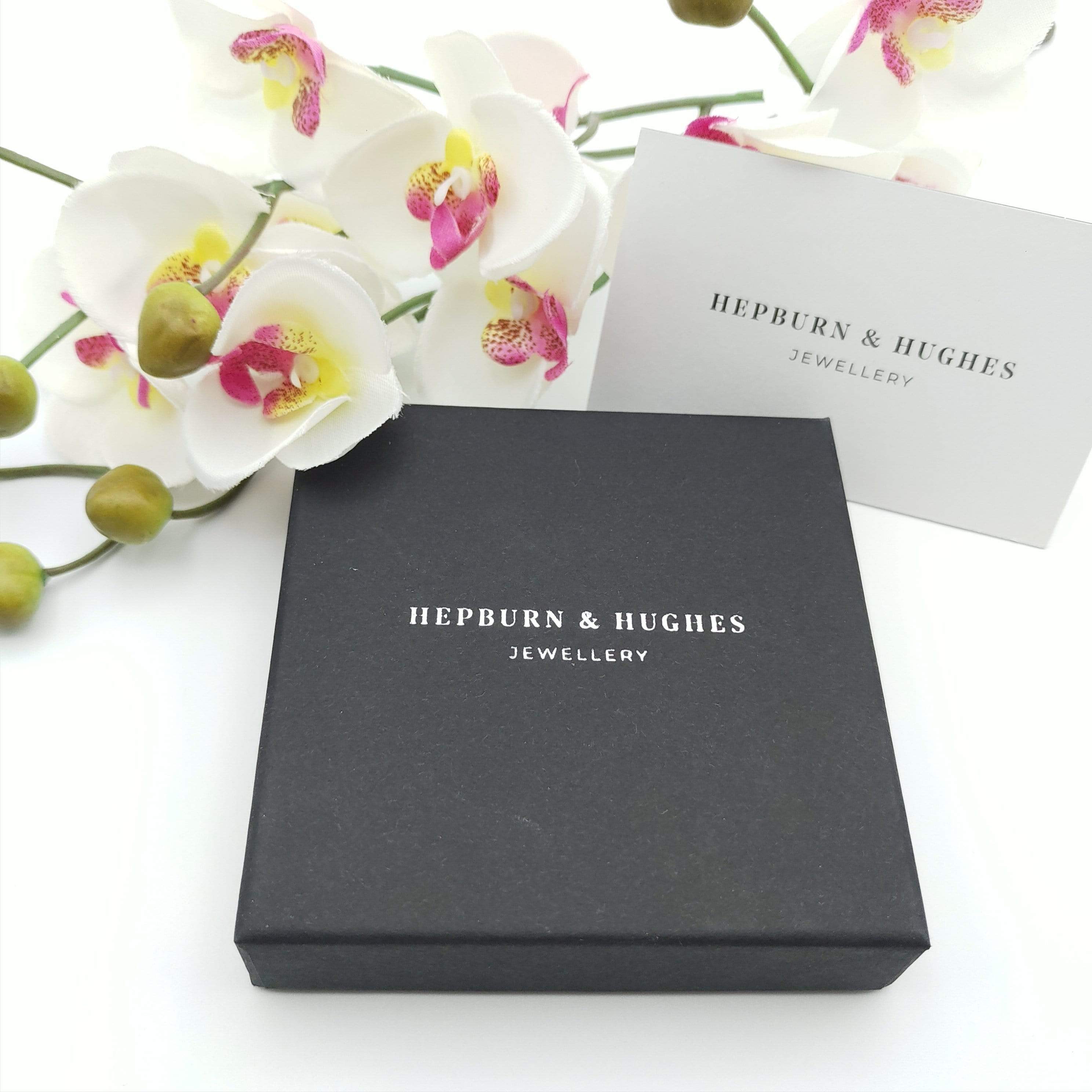 Black jewellery box with Hepburn & Hughes logo in silver, white background and an orchid above