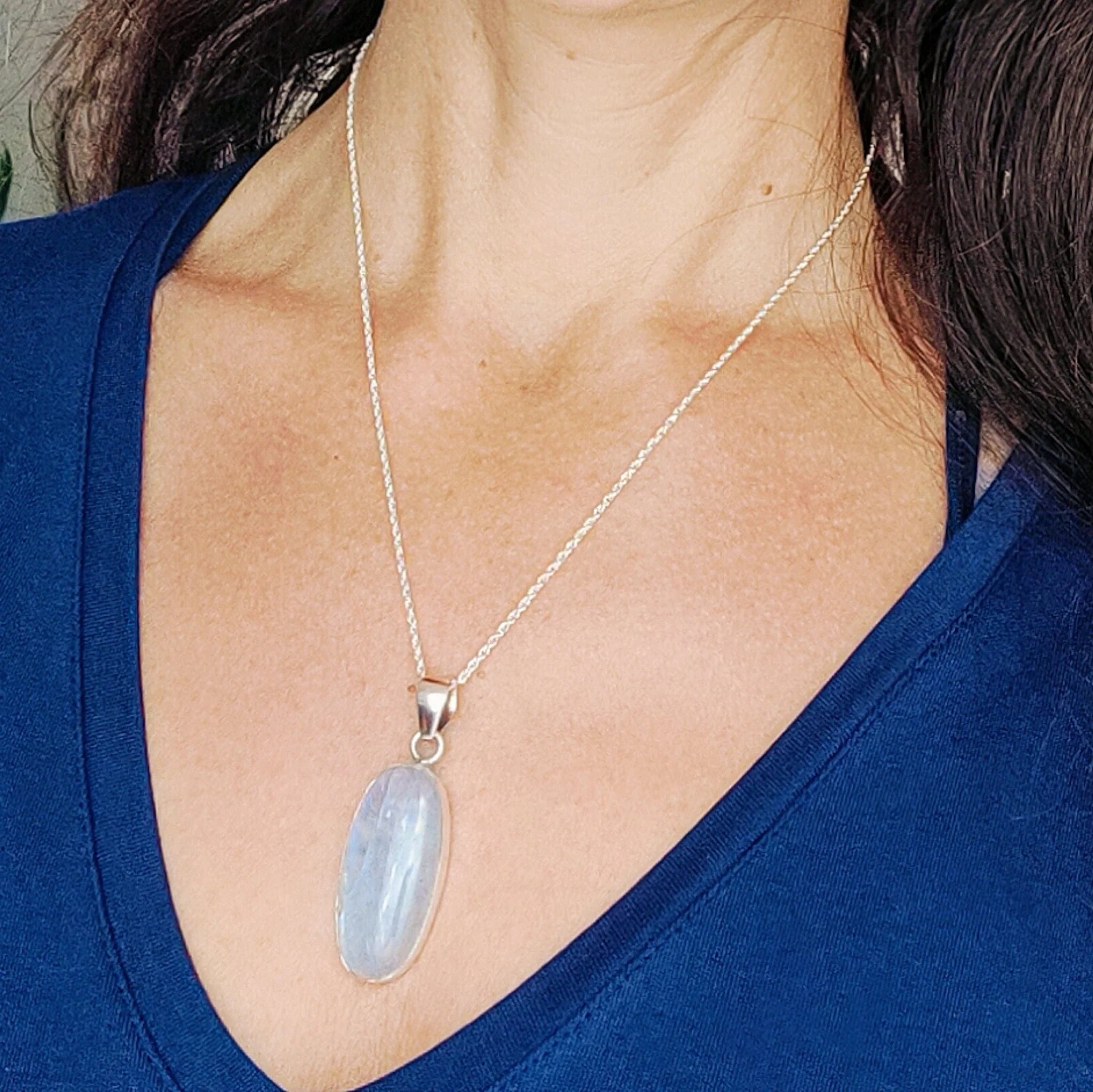 june birthstone- a moonstone silver pendant in oval worn by Zoe with a blue top 