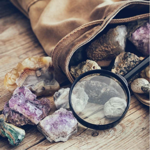 Gemstones with a magnifying glass, falling out of a bag