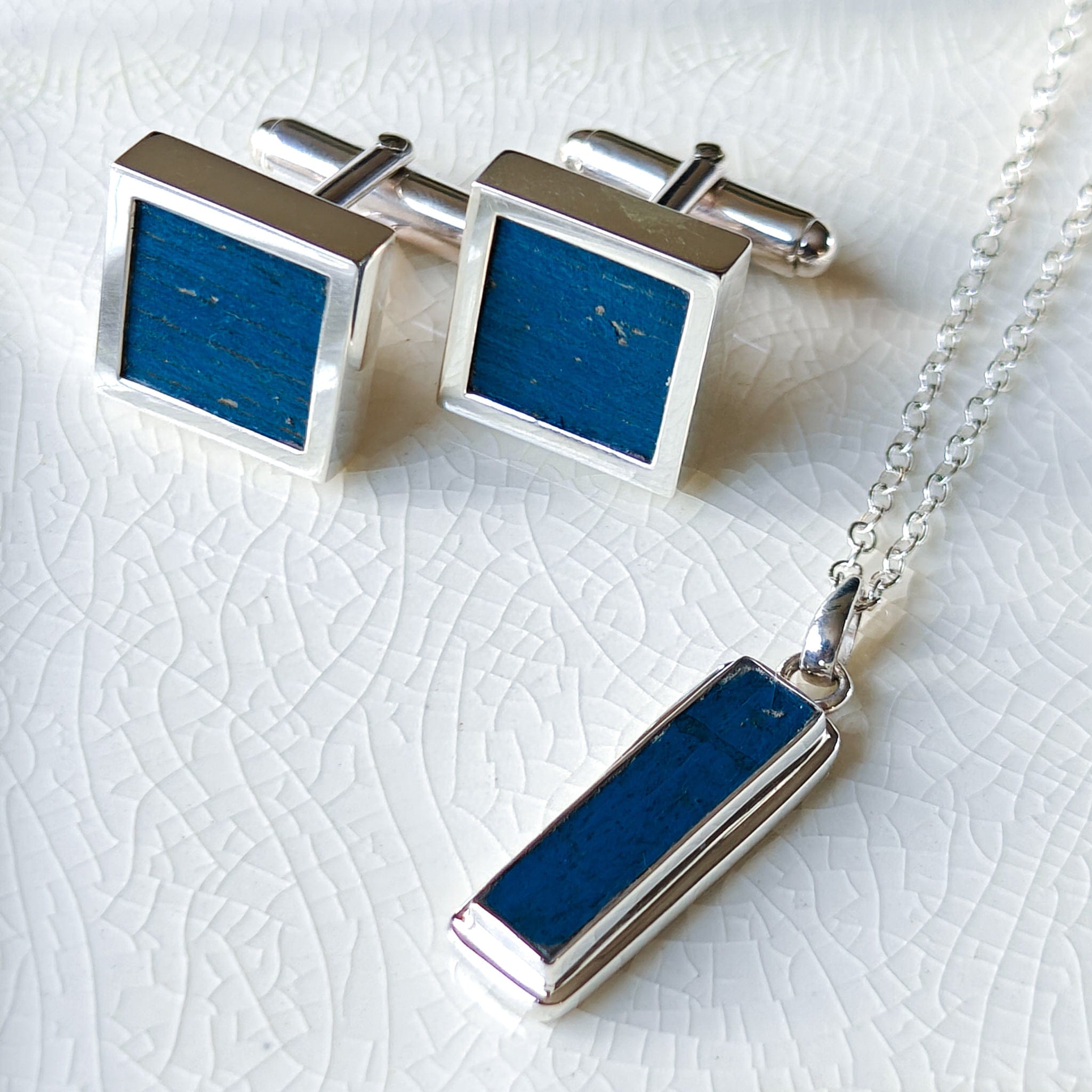 Wembley stadium square cufflinks and rectangle pendants in sterling silver on crackled ceramic background 