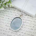 Hepburn and Hughes Aquamarine Sterling Silver Pendant, showing the back of the stone and the silver band, on antique paper
