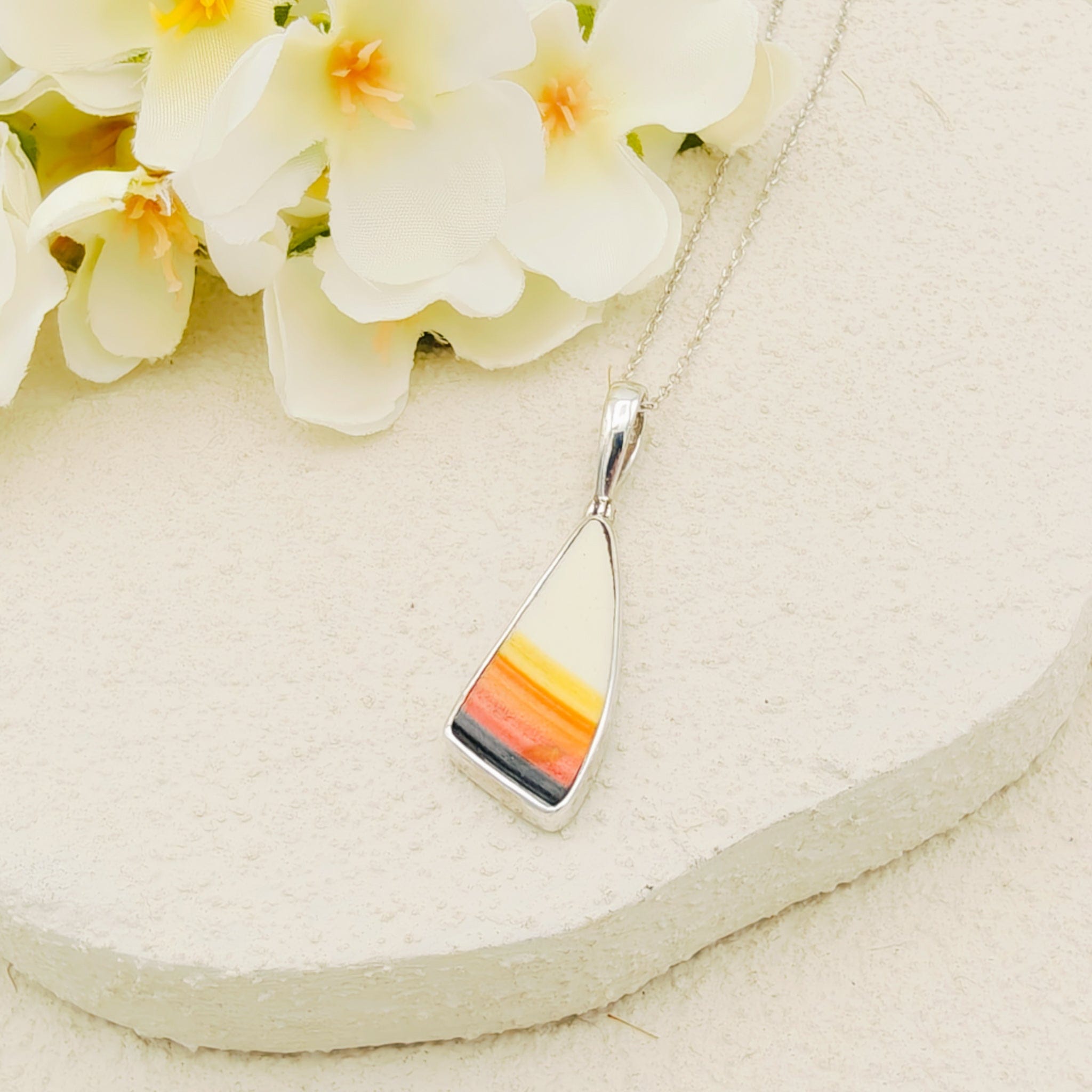 White, orange, yellow and black triangle Clarice Cliff pendant with a silver chain, one of the triangle sides is curved. 